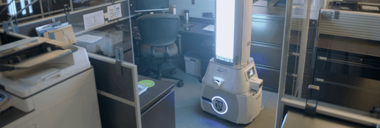 Robot désinfectant en action dans un cubicule de travail.